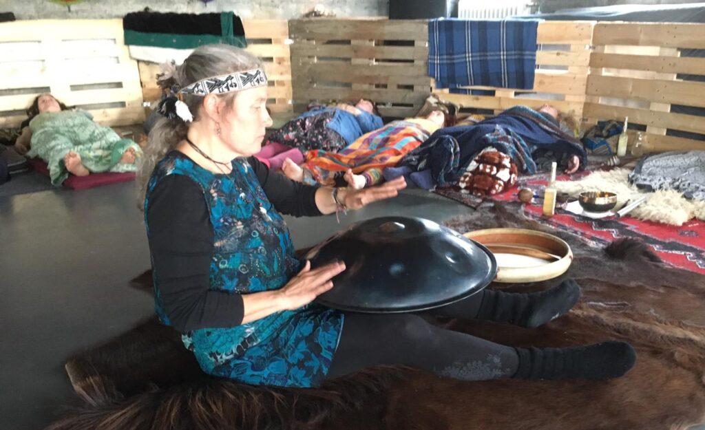 Annette Lachmann sitzt zwischen Instrumenten und spielt Handpan
