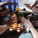 Mehrere Hände umgeben Kerzen und einen Zeremonienaltar
